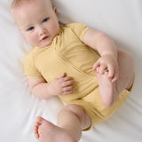 Baby lying on white bedding wearing Sunglow bamboo shorty pajamas