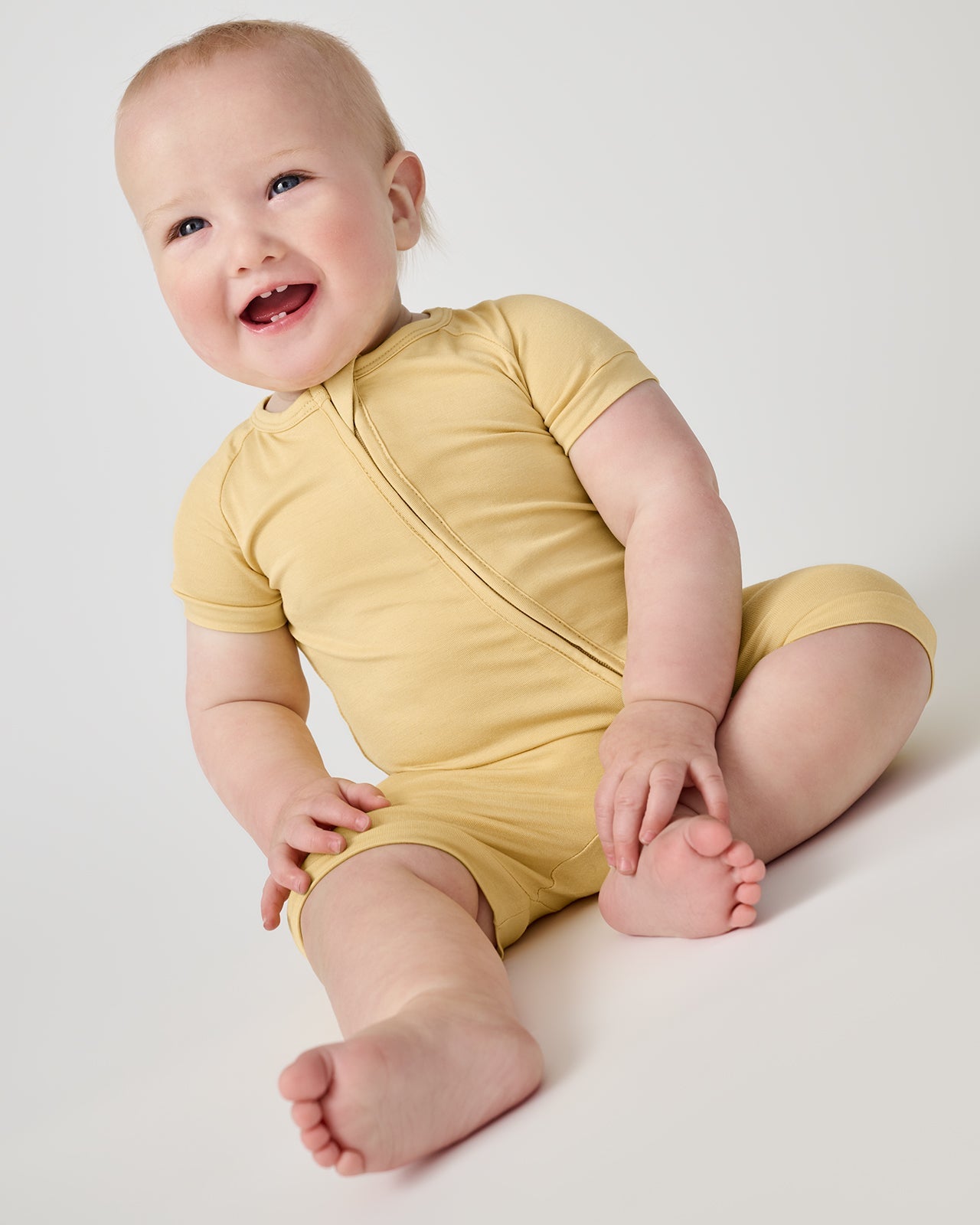 Smiling baby wearing the Sunglow yellow bamboo shorty zippy pajamas