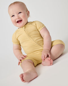 Smiling baby wearing the Sunglow yellow bamboo shorty zippy pajamas