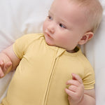 Baby resting on white bedding in Sunglow bamboo shorty pajamas